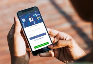 A photo of iPhone X in hands of a female with Facebook login screen open