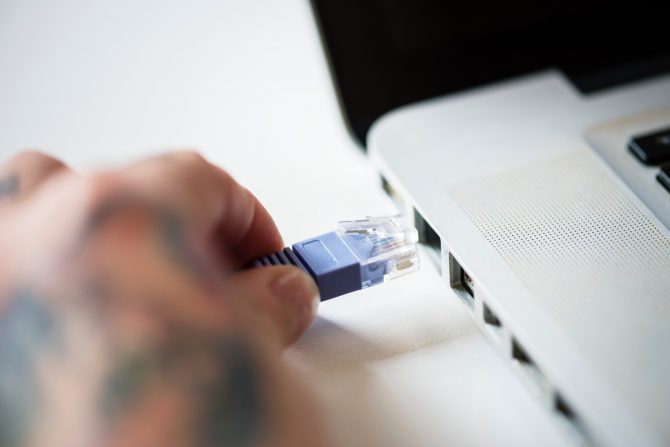 How To Increase Your Internet Speed 2 A Hand Plugging In An Ethernet Port To The Laptop