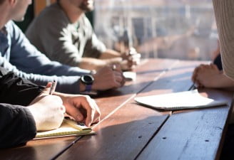 A photo of people sitting on a table discussing