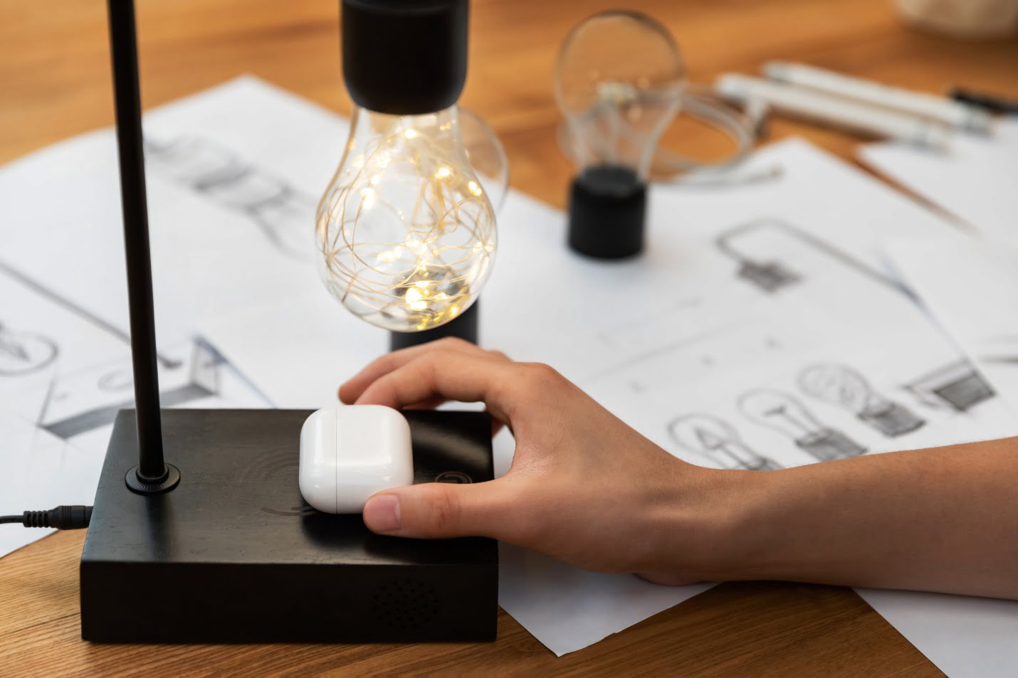 Latest Trend: Wireless Electricity Meets Levitation In This New Gadget 2 A Woman Is Placing Her Airpods To Wirelessly Charge On Gravita Lamp