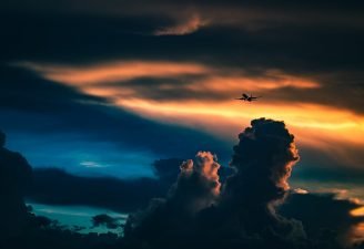 An Airplane passes through clouds during sunset