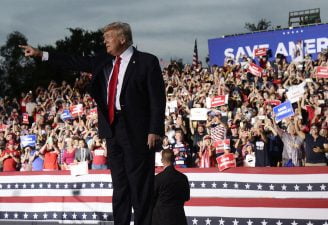 Trump waving hands while seeing his supporters