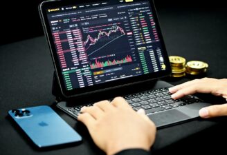 A person checking his crypto investment on his iPad with an iPhone placed near on a table